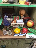 Overall view of vintage kitchen decor items arranged on a wooden surface includes various animal figurines, ceramic vegetables, and assorted vintage boxes and containers.