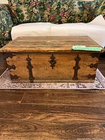 Front view of wooden chest coffee table showing iron strap hinges and hardware