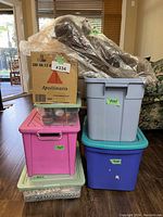 Photo of stacked bins and boxes showing different storage containers holding Christmas décor items including a cardboard box and a wrapped large woven reindeer figure.