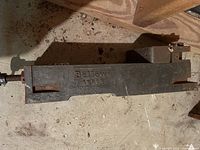 Full view of the Bellows Akron heavy duty vice lying on a concrete floor showing 'Bellows Akron' embossed on the side body.