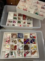 View of multiple divided trays with various small Christmas ornaments like snowmen, Santas, reindeer, nutcrackers