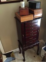 Full view of the wooden jewelry cabinet with four jewelry boxes and a jewelry cleaner jar on top