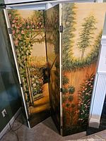 View showing three of the four garden-themed painted panels of the folding room screen with floral and tree imagery.
