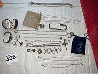 Full overview of the lot including cuff bracelet, rings, chains, pendants, pin, and bracelets on a light fabric background.