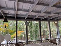 Porch view showing outdoor thermometer mounted on frame and some visible hanging wind chimes.