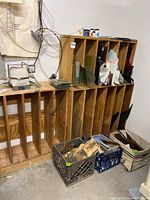 Wide shot of three wooden cubby racks against wall filled with various glass panels and crates