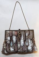 Front view of the 1930s vintage dusty rose purse adorned with sequins and pearls in a scale pattern, showcasing the brass chain handle and clasp.