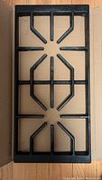 Top view of a single black cast iron rectangular gas burner stovetop grill showing the geometric pattern of bars