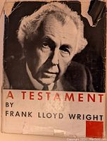 Front cover of 'A Testament' by Frank Lloyd Wright showing a black and white portrait photograph with damaged dust jacket edges.