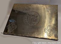 Top view of brass Bible stand showing four etched crosses and central IHS monogram.