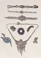 Top view of all rhinestone jewelry pieces arranged flat on light background showing bracelets, necklace, and brooches
