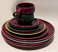 Stacked set of ceramic cups, saucers, medium and large plates showing the colors and sizes.