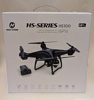 Front view of the white sealed box featuring Holy Stone HS-Series HS100 FPV drone with image of black quadcopter drone and key features listed on box.