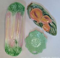 Three ornamental plates laid out: celery plate, leaf plate, and orange fruit plate
