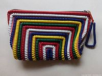 Front view of rectangular clutch purse decorated with concentric rectangles formed from different colored telephone cord material. Colors visible include red, blue, yellow, white, and green. Zipper closure present with a red zipper pull and matching blue wrist strap.