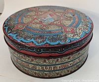 Side view of the round tin showing detailed ornamentation and part of the brand text Wonder Fruit Cake.