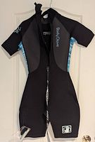 Rear view of the wetsuit hanging, showing the zipper and Body Glove logos on the sleeve and lower leg with aqua blue striped gussets on sides.