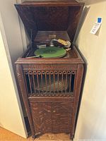 Antique Acme phonograph machine with lid open, showing green felt turntable and internal records stored inside cabinet