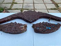 Top view shows the long, intricately carved central section with floral and scroll motifs, flanked by two broken wing-shaped pieces below.