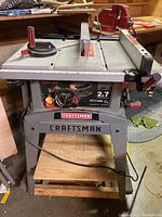 Front and top view of Craftsman 10 inch table saw on rolling dolly. Shows controls, handles, and table surface.