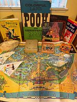 Full view of vintage Disneyland map, assorted vintage Disney books, and ephemera on a flat surface near a window.