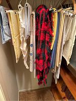 Hanging linens including cream, beige, blue, yellow, and a red and black plaid fringed piece