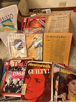 Photo showing a variety of historic magazines and newspapers including McClure's magazines in plastic protective wrapping, Time and Newsweek magazines, and historic newspapers like The Garden City Paper and Los Angeles Times.