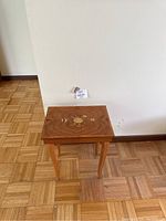 Full view of the wooden side table against a plain wall, showing top surface and legs.