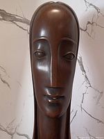 Close-up of the bust's face showing stylized almond eyes, long nose and lips with some wear.