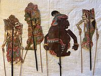 Full set of five Southeast Asian shadow puppets laid on fabric background, showing size, condition, and details of the puppets.