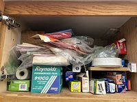 Cabinet shelf photo showing assortment of storage bags, food wrap boxes, and plastic bags.