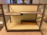 Side-angle view of the curio cabinet displaying the glass panel sides and stepped wooden shelves inside.