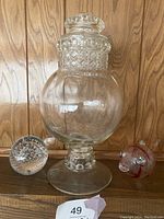 Front view of the vintage globe-shaped glass candy jar with lid, and the two accompanying glass items, a bubble paperweight and a glass painted fish sculpture