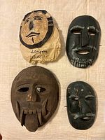 Four vintage Southeast Asian wooden masks shown together including one marked Lampung