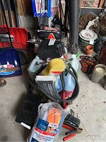 Photo showing windshield fluid containers, jumper cables with clamps, microfibre towels, trailer hitches, and snow scrapers in background.