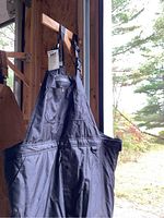 Full view of one black Dakota insulated coverall bib hanging showing multiple pockets and adjustable shoulder straps.