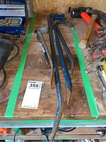 Five metal crow bars laid on wooden workbench with some rust and paint wear visible.