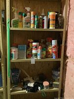 Wooden shelf with three shelves containing multiple gardening supplies such as sprays, bottles, gloves, and small containers.