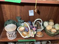 Wide angle showing porcelain baskets with several marble eggs and spherical stones along with an oval marble dish containing marble eggs.