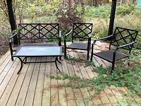 Full view of the 4 piece metal framed patio set including loveseat, two chairs, and coffee table on a wooden deck outside.