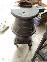 Front view of cast iron pot belly stove showing rounded body, removable top lid and flue collar