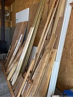 Photo showing various lumber pieces leaning against wall including plywood sheets and trim
