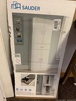 Photo of the box packaging showing the Sauder brand utility cabinet and shoe rack with measurements 15x72 inches
