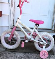 Side view of the Huffy 12 inch Sea Star bike showing pink and white color scheme, training wheels, and condition of the bike