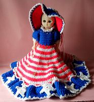 Front view of the 14-inch doll wearing the crocheted red, white, and blue dress with star details and bonnet.