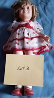 Front view of the Shirley Temple doll holding a card labeled Lot 3 to identify the lot.