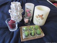 Photo showing all candles in the assortment including carved, floral and butterfly candles, votive candles in glass holders, and boxed cactus-shaped candles.