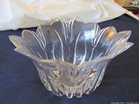 Clear tulip-petal shaped crystal vase, viewed from the side to show faceted design and form.