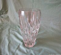 Large pinkish hue crystal vase standing upright on fabric background