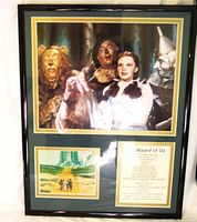 Framed wall hanging with image of Dorothy and her companions from Wizard of Oz, yellow brick road scene, and related text.